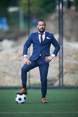 business man posing with a ball on his foot inside a soccer field © Imaxepress