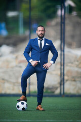 business man posing with a ball on his foot inside a soccer field