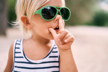 Little girl in sunglasses touches her nose with her finger. Portrait. High quality photo