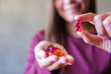 Closeup image of a woman holding and showing at a red jelly gummy bears