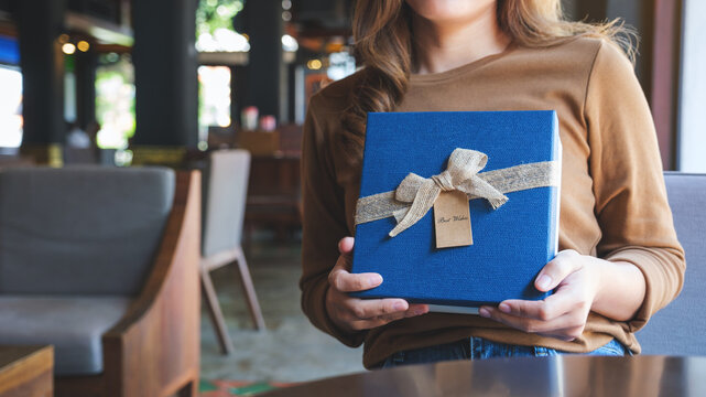 Closeup image of a young woman holding and receiving a present box