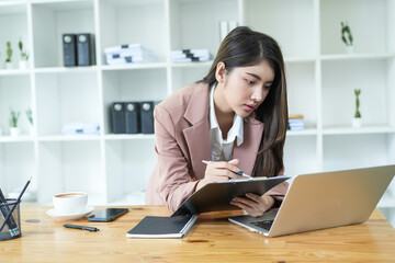Asian business woman Use a laptop computer and work at the office ready. plan to analyze financial reports