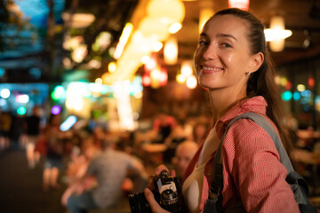 Traveller backpack woman take photo in Yaowarat street at night traditional asia city