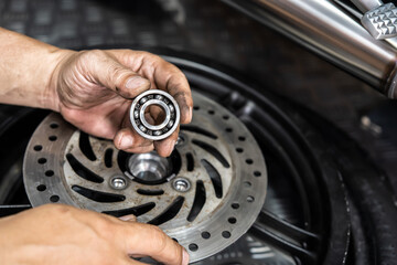 Mechanic check and replace Motorcycle wheel bearings , working in garage . repair and  maintenance...