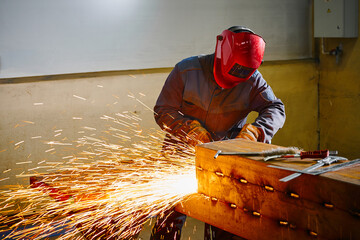 Welder in mask cuts steel beam with cutting blowpipe in shop