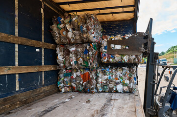 Forklift truck loads pressed plastic pack on shelf in yard