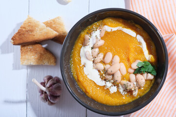 Orange hot pumpkin lentil soup in bowl. Spicy creamy soup with pumpkin puree. autumn soup, healthy meal for winter season. Vegetarian pumpkin puree.