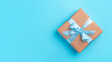 Gift box with a blue ribbon on a blue background. The concept of holidays. Top view, horizontal
