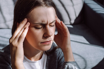 Close up of stressed young caucasian woman touching head and feels dizzy, suffering from headache...