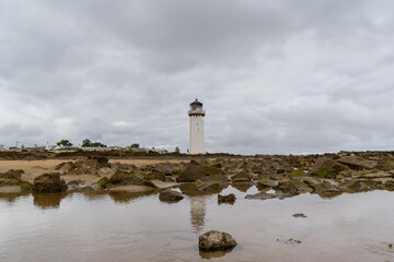 the historic Southerness Lighthouse in Scotland with reflections in tidal pools in the foreground