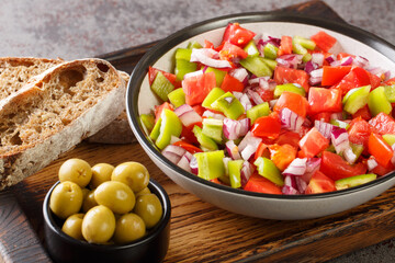 Trampo ensalada salad made with tomatoes, peppers, and onions served with olive and bread closeup on the wooden board on the table. Horizontal
