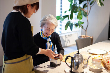 Fototapeta カフェでスマートフォン決済をするシニア女性 obraz