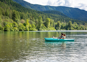 Fototapeta na wymiar Two women Kayaking on a pristine mountain lake in the state of Washington Pacific Northwest. Scenic landscape horizontal photo of two friends enjoying the great outdoors together