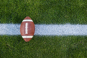 View from above of an American Football sitting on a grass football field on the yard line. Generic...