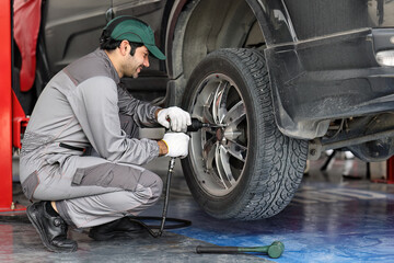 Obraz premium Mechanic changing a wheel of a modern car
