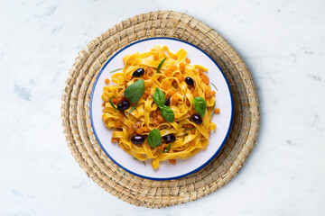 Pasta ribbons with sautéed pumpkin and black olives. Traditional Italian recipe.