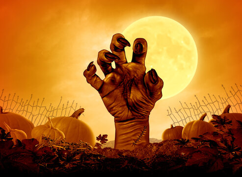 Halloween monster night poster and Autumn party background with a scary zombie hand with a yellow moon glowing on a grungy old creepy pumpkin patch