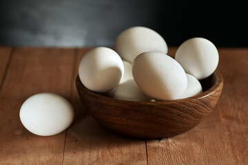 Chicken eggs in a wooden bowl on a wooden surface. Easter