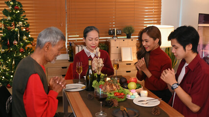 Beautiful family praying before holiday dinner at home. Christmas, New year, thanksgiving, holidays and celebration concept