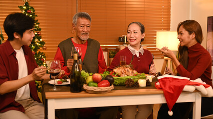 Joyful family talking and celebrating Christmas at dining table. Holidays and celebration concept