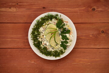 Olivier salad is decorated with herbs. Winter salad. Lime. food. for a festive table. on a wooden background.	
