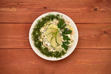 Olivier salad is decorated with herbs. Winter salad. Lime. food. for a festive table. on a wooden background.	