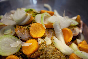 A raw sliced meat, pickled with spices, and vegetables for further cooking.