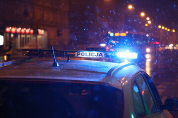 Polska policja na służbie zimą w czasie opadów śniegu wieczorem.  - obrazy, fototapety, plakaty