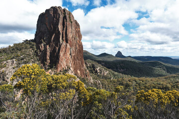 A photograph of Bluff Mountain and surrounding valleys against a cloudy blue sky taken in the Warrumbungle National Park