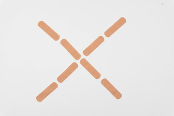 Cross made with band aids. White background.