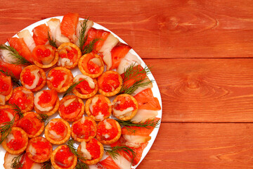 Tartlets with red caviar. Salmon caviar close-up. sliced white fish. Red fish. on a plate. Delicious food. The texture of caviar. Seafood appetizer. in the store. on a wooden background.
