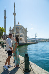 Couple in love gazing into each other's eyes with the ortakoy mosque and the famous istanbul bridge in the background.