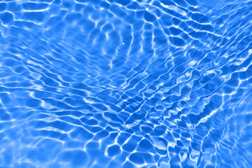 Bluewater waves on the surface ripples blurred. Defocus blurred transparent blue colored clear calm water surface texture with splash and bubbles. Water waves with shining pattern texture background.