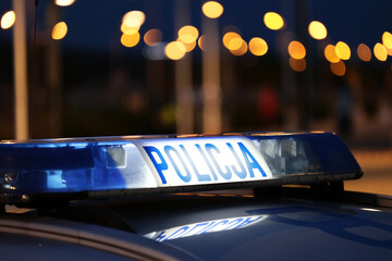 Nocna interwencja alarmowa policji - Sygnalizator błyskowy niebieski na dachu radiowozu policji polskiej w nocy.