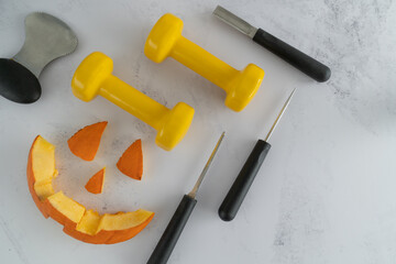 Dumbbells with Halloween pumpkin pieces cut out. Carved face elements with carving tools, spoon...