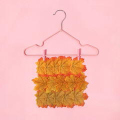 Autumn creative layout made with leaves and clothes hanger on pastel baby pink background. Vintage retro aesthetic 80s or 90s fashion concept. Minimal autumn season idea.
