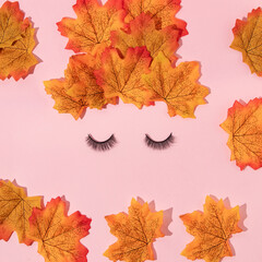 Autumn creative layout made with leaves and false eyelashes on pastel baby pink background. Vintage retro aesthetic 80s or 90s fashion concept. Minimal autumn season idea.