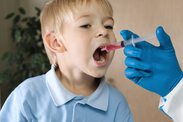 Kid getting polio drops. Doctor making to Child Oral Vaccination against infection. Little Blonde...