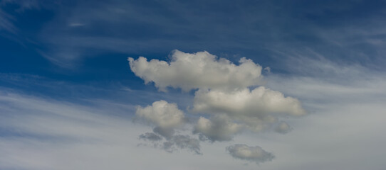 Naklejka na ściany i meble Cumulus clouds on stratus background on blue sky.