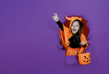 Little devil girl on a purple background is celebrating Halloween