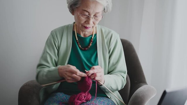 動画を観ながら編み物をするシニア女性