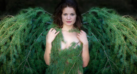 young beautiful sexy brunette woman with fir branches and spruce wings as Christmas angel