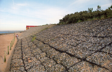sea wall defenses stones in wire cages on beach. location Wells-next-to-Sea Norfolk UK