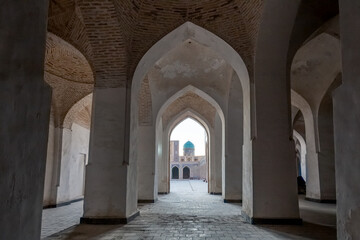 Fototapeta na wymiar Empty colonnade covered with arched roof in the courtyard of ancient mosque, Bukhara, Uzbekistan