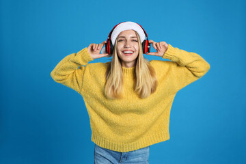 Happy woman with headphones on blue background. Christmas music