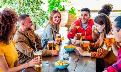 group of friends celebrating happy hour drinking beers at bar restaurant indoor having fun together. happy young people sitting on pub table cheering and smiling. joy, friendship and lifestyle concept