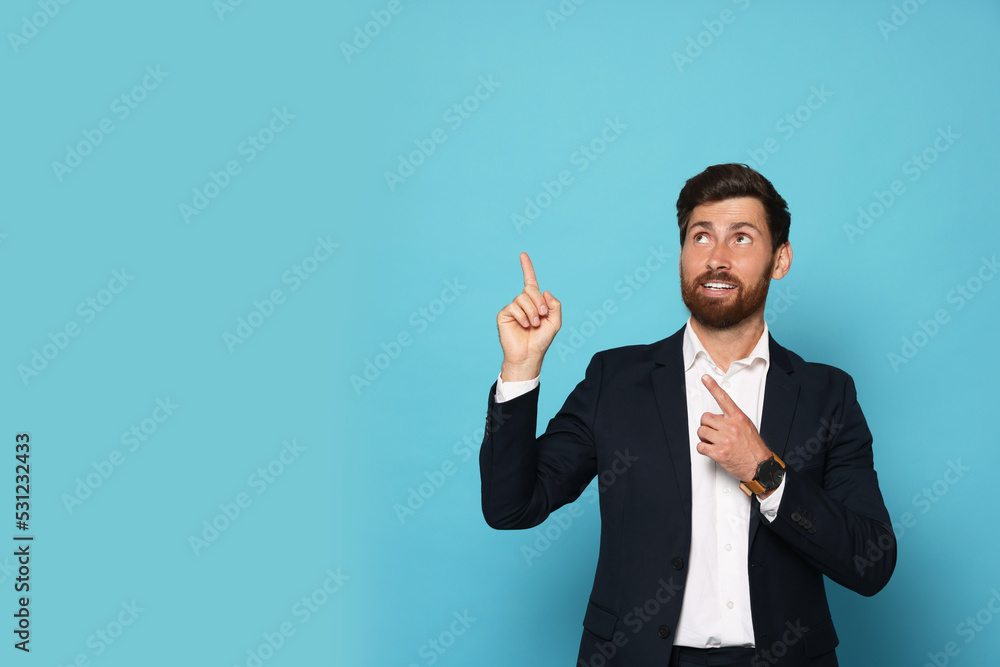 Poster smiling bearded man pointing index fingers up on light blue background. space for text