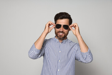 Fototapeta premium Portrait of smiling bearded man with sunglasses on grey background