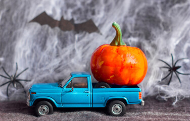  Car toy pickup truck decorative pumpkin on the background of the web of a spider and a bat Halloween holiday theme, selective focus