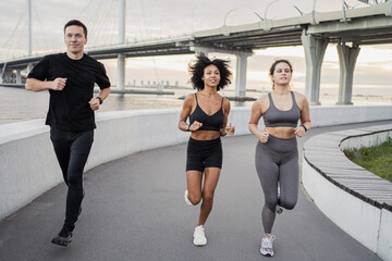Use a fitness watch bracelet on the arm. A group of people are training running fitness in the city.